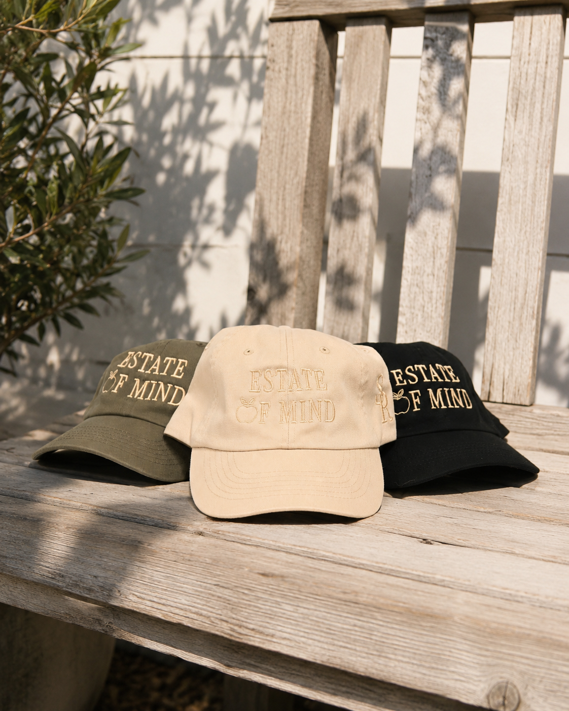 Three hats in beige, green, and black on a wooden surface with a natural background.