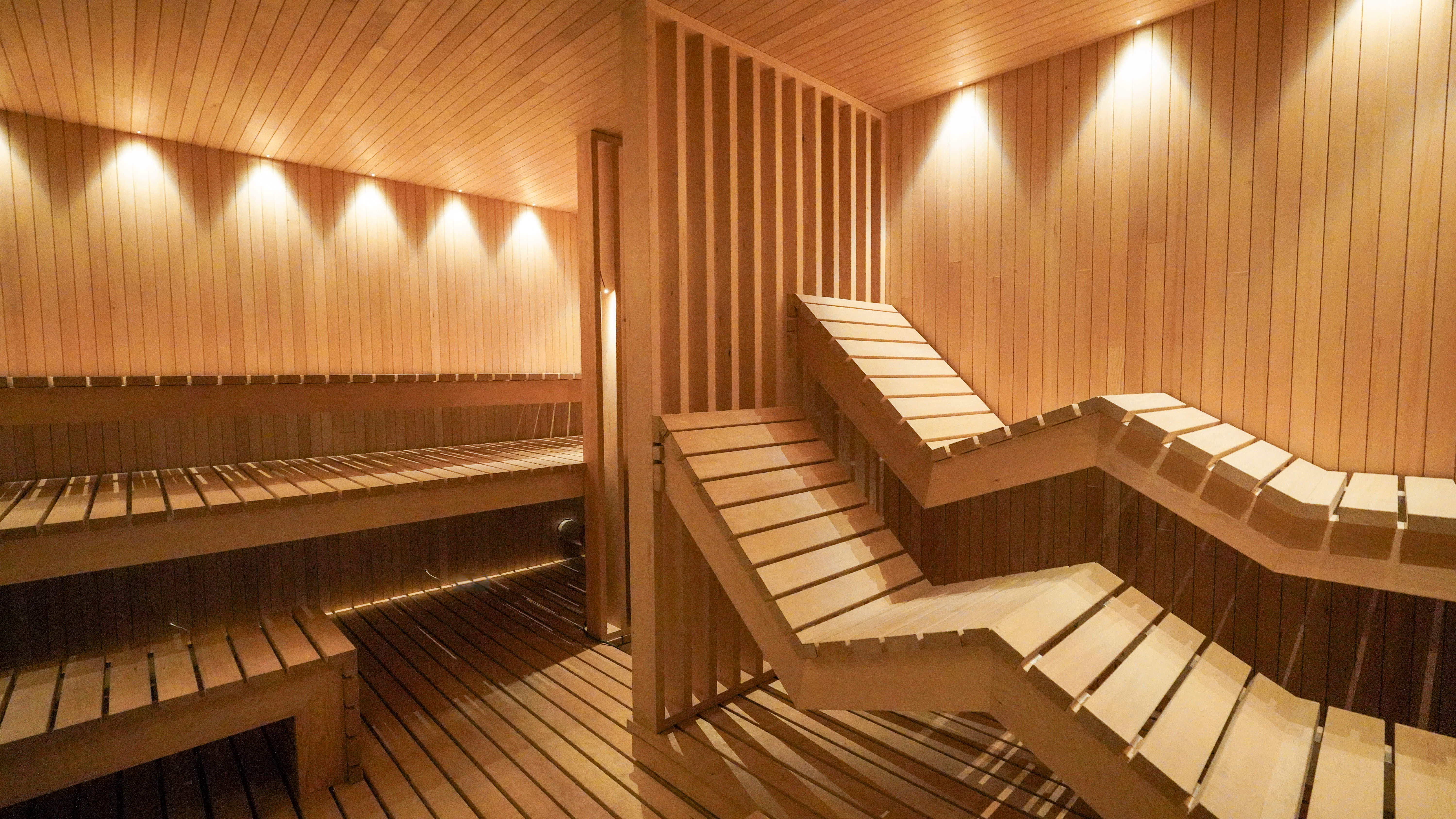 Interior of a wooden sauna featuring benches and warm lighting, designed for relaxation.