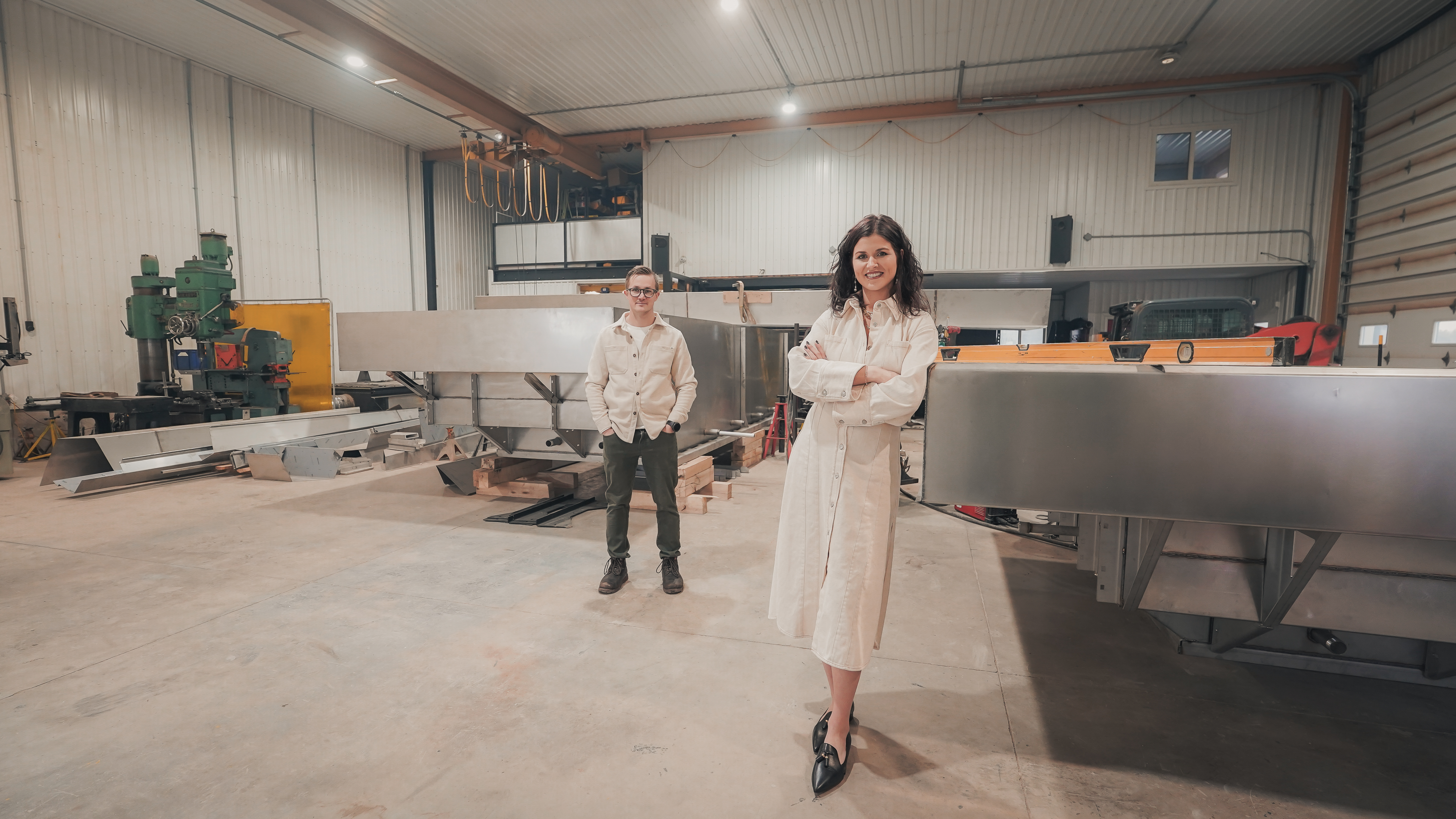 Founders standing in a large industrial workshop with stainless steel spa components and heavy machinery.